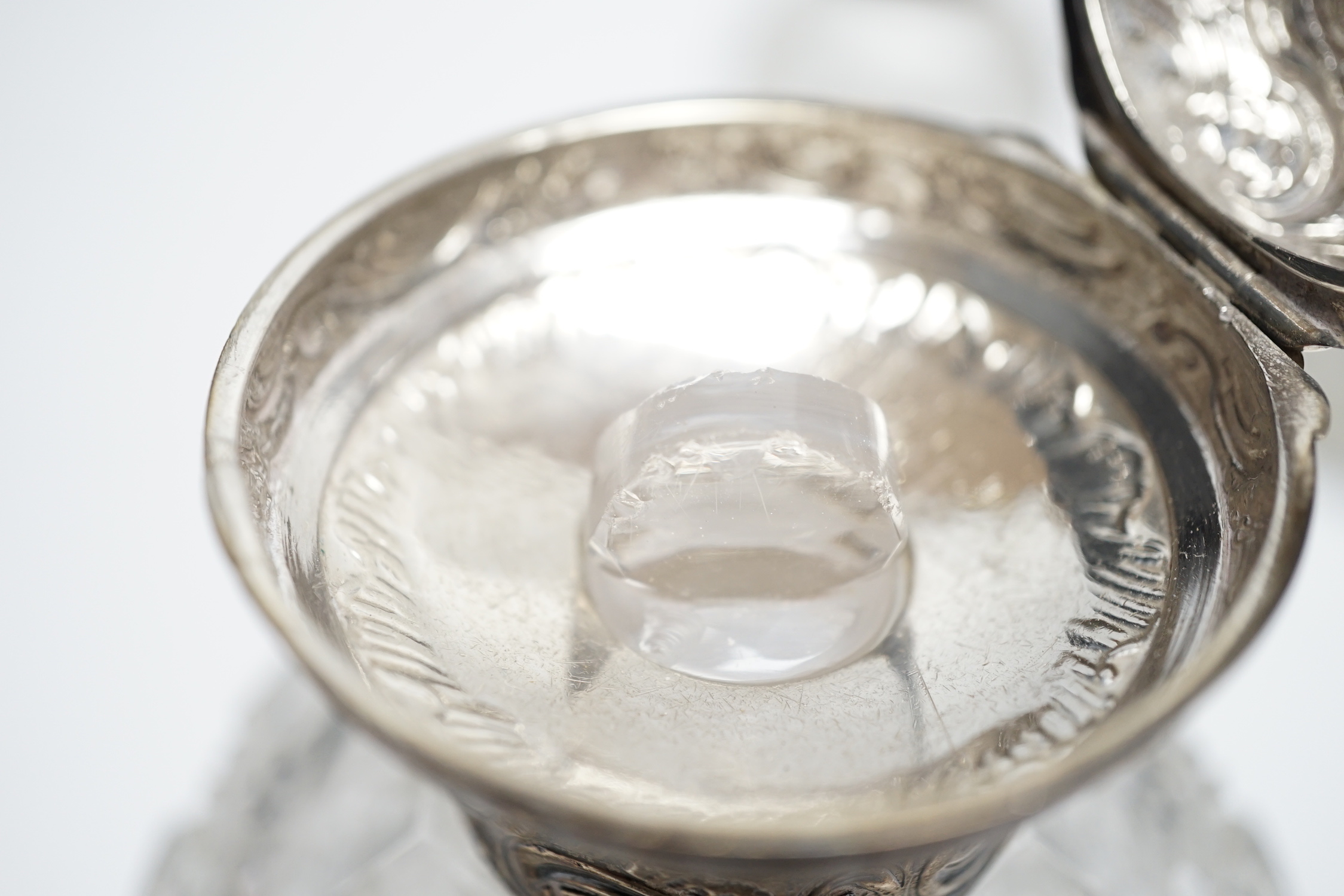 A late Victorian repousse silver mounted travelling pocket watch case, Birmingham, 1898, 11.6cm, with nickel cased pocket watch, together with five silver topped glass toilet jars.